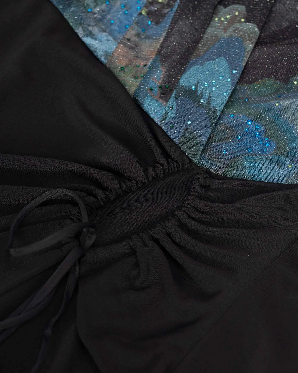 The black fabric gathers towards the waist beneath the contrasting upper section.