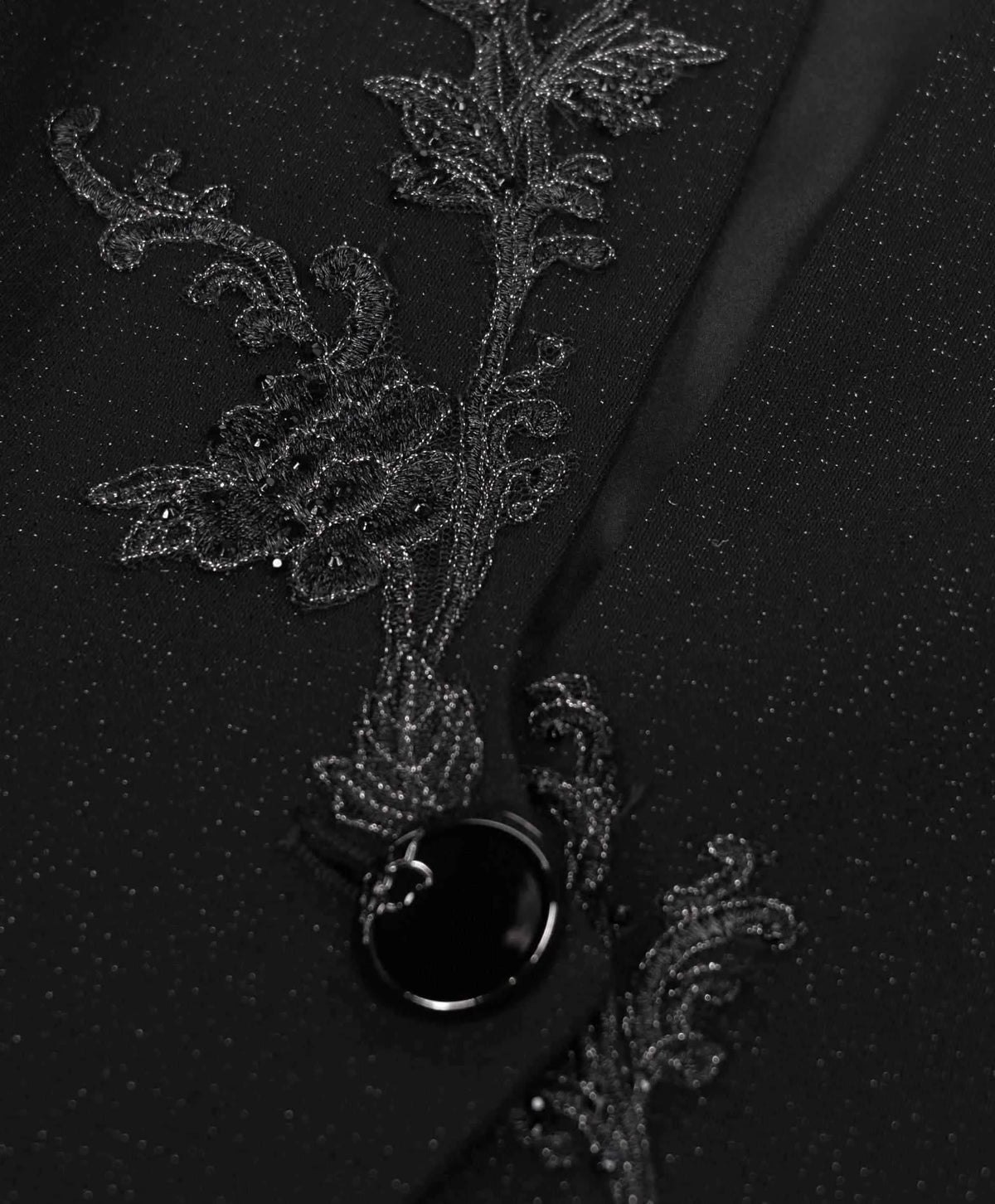 A tonal embroidered branch runs beside the front edge and dark button.