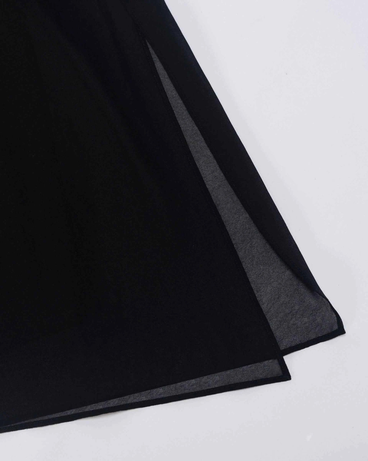 A fine transparent layer extends below the darker trouser leg, forming a light border at the hem.