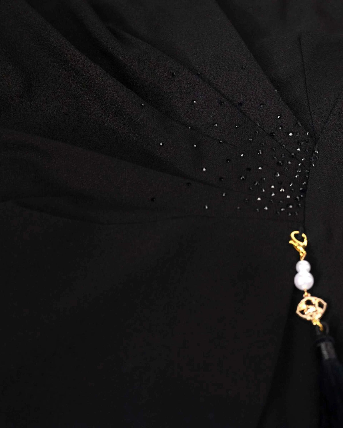 A small hanging ornament sits beneath reflective accents at the gathered waist.
