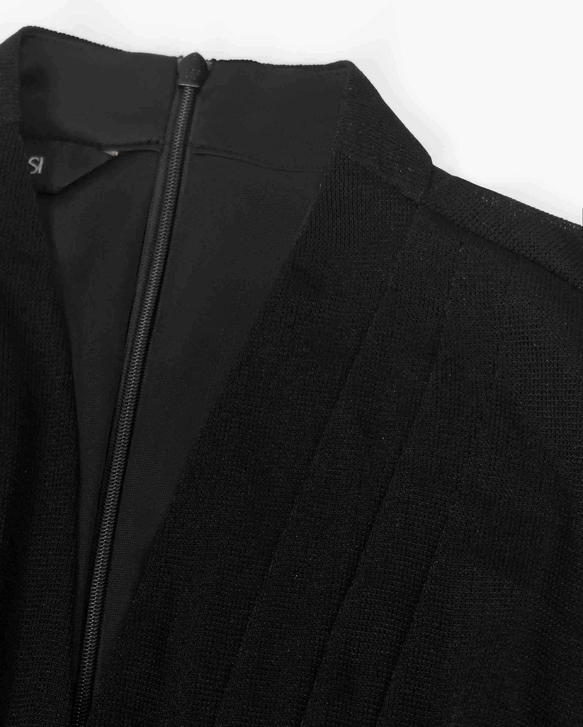 The raised neckline and back fastening introduce clean vertical details beside the softly arranged fabric.