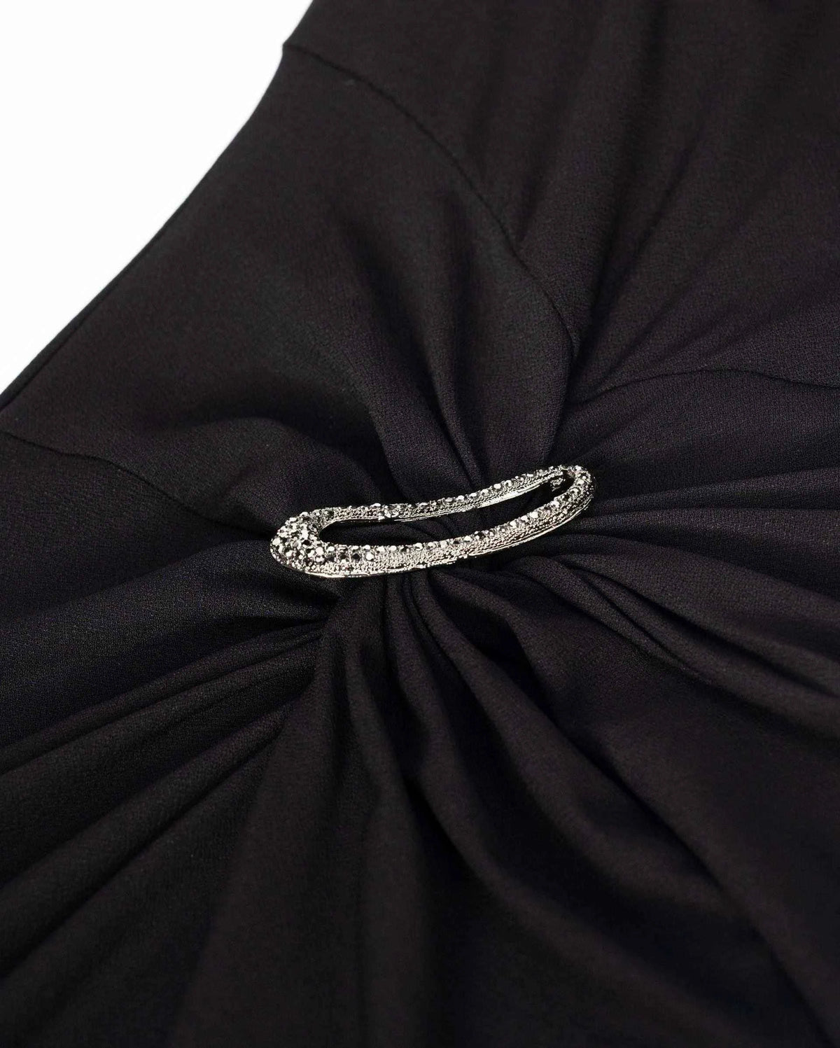 An oval decorative accent sits among gathered black folds at the waist.