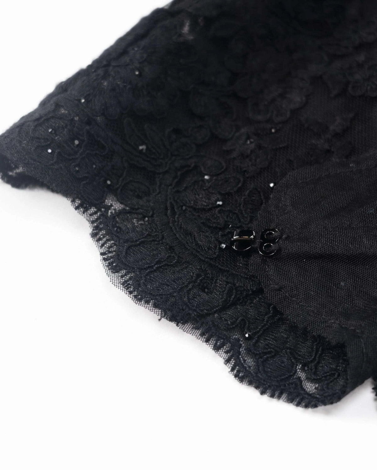 The lace ends in a curved scalloped border, with small reflective accents visible within the floral texture.
