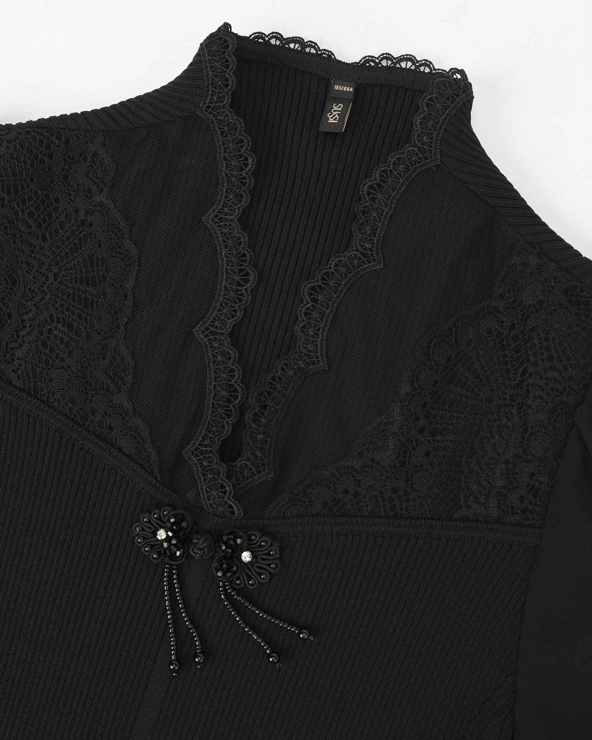 Lace borders and decorative fastenings follow the front of the black top.