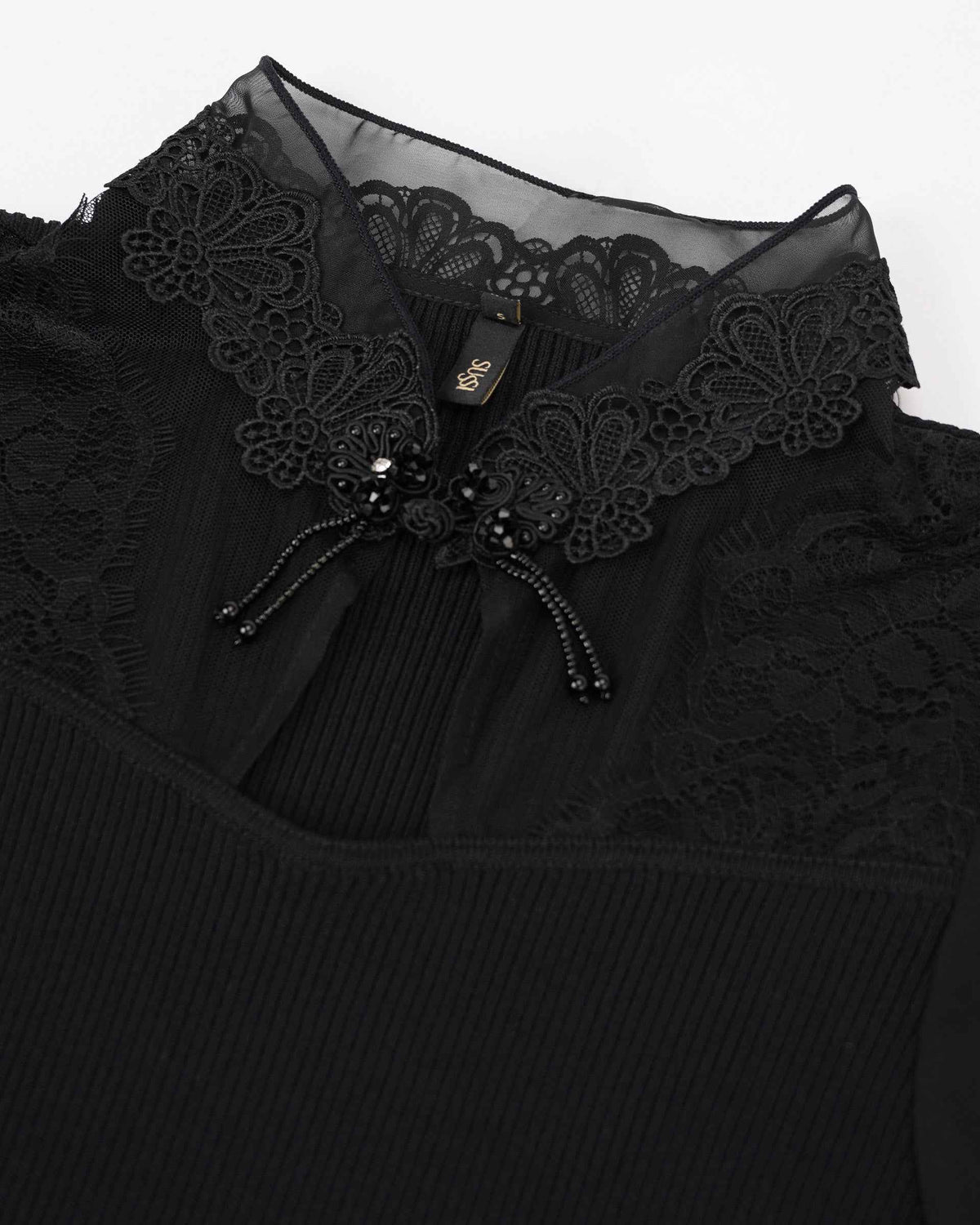 A shaped lace collar frames the neckline, with a small decorative accent at its centre.