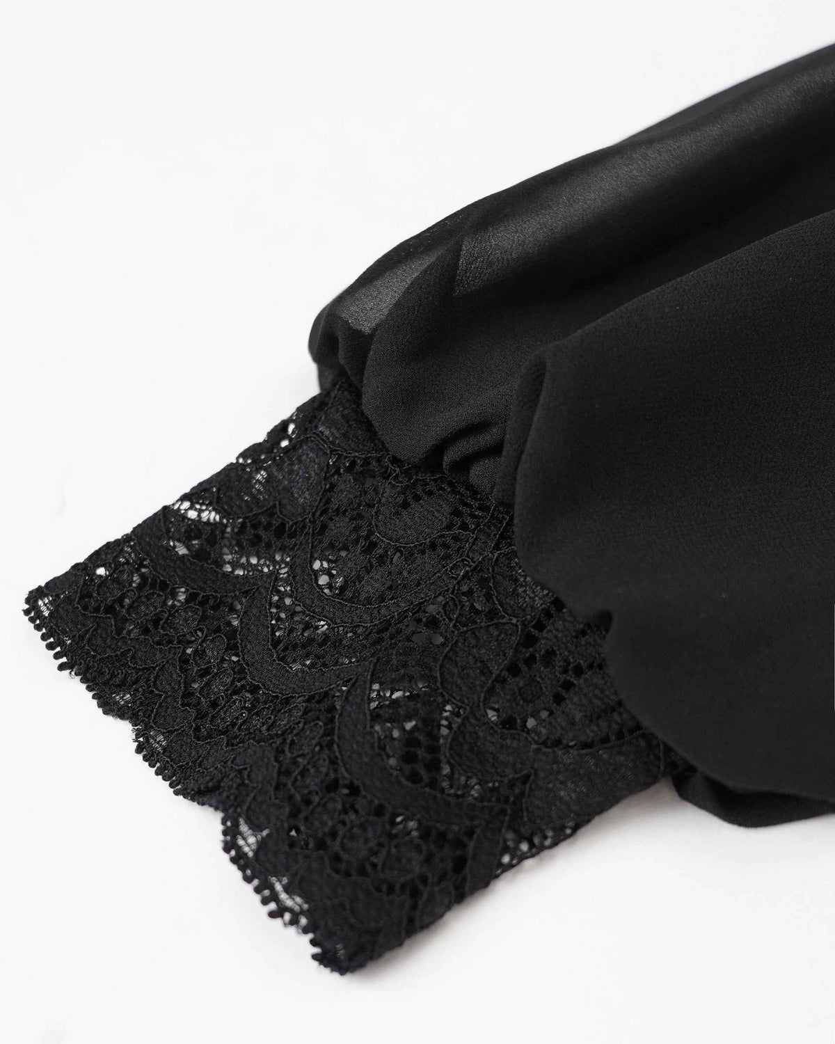 The smooth sleeve gathers into a lace cuff, where floral shapes create a more intricate finish.