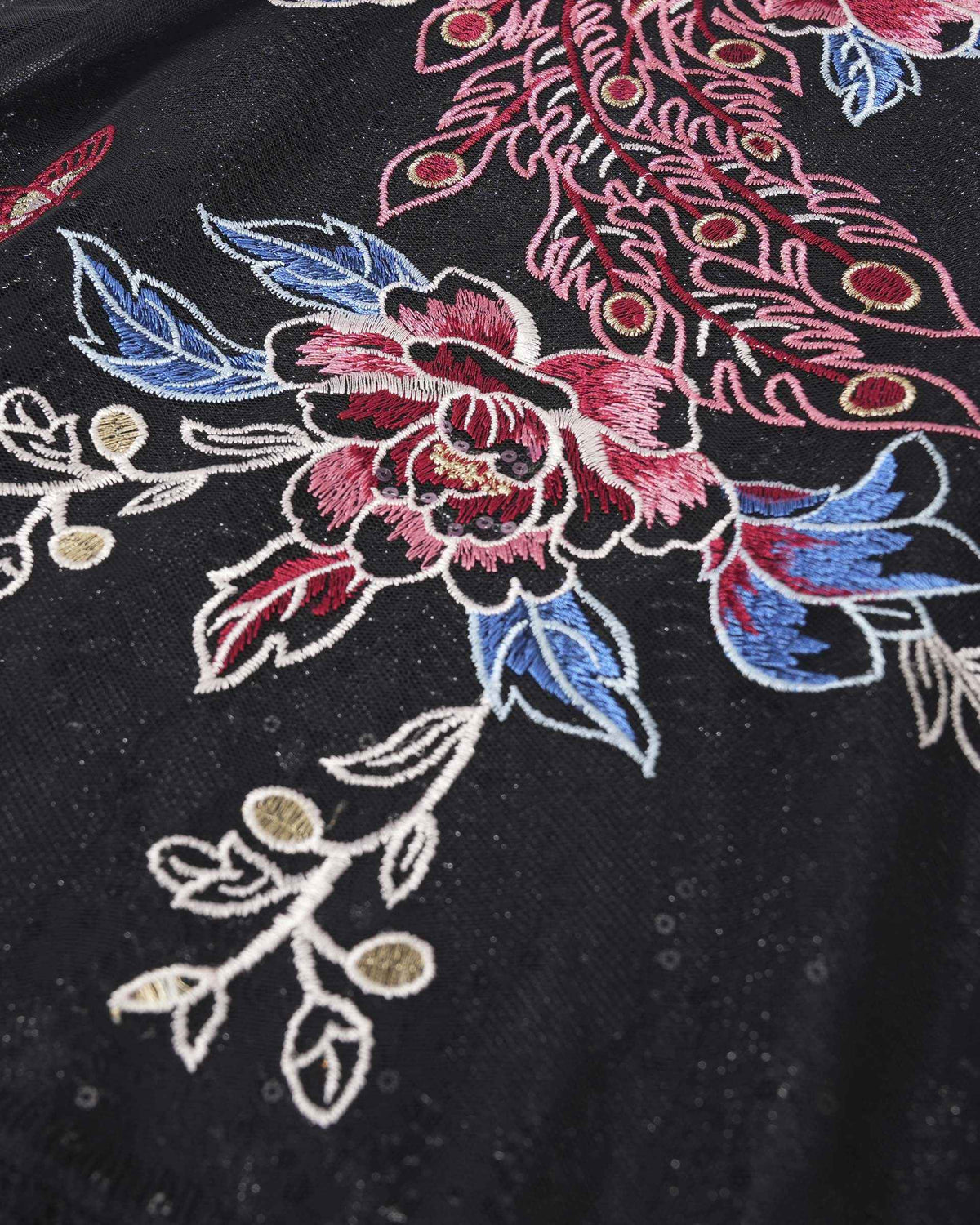 Pink, blue, and pale threads outline flowers and leaves against the dark ground.