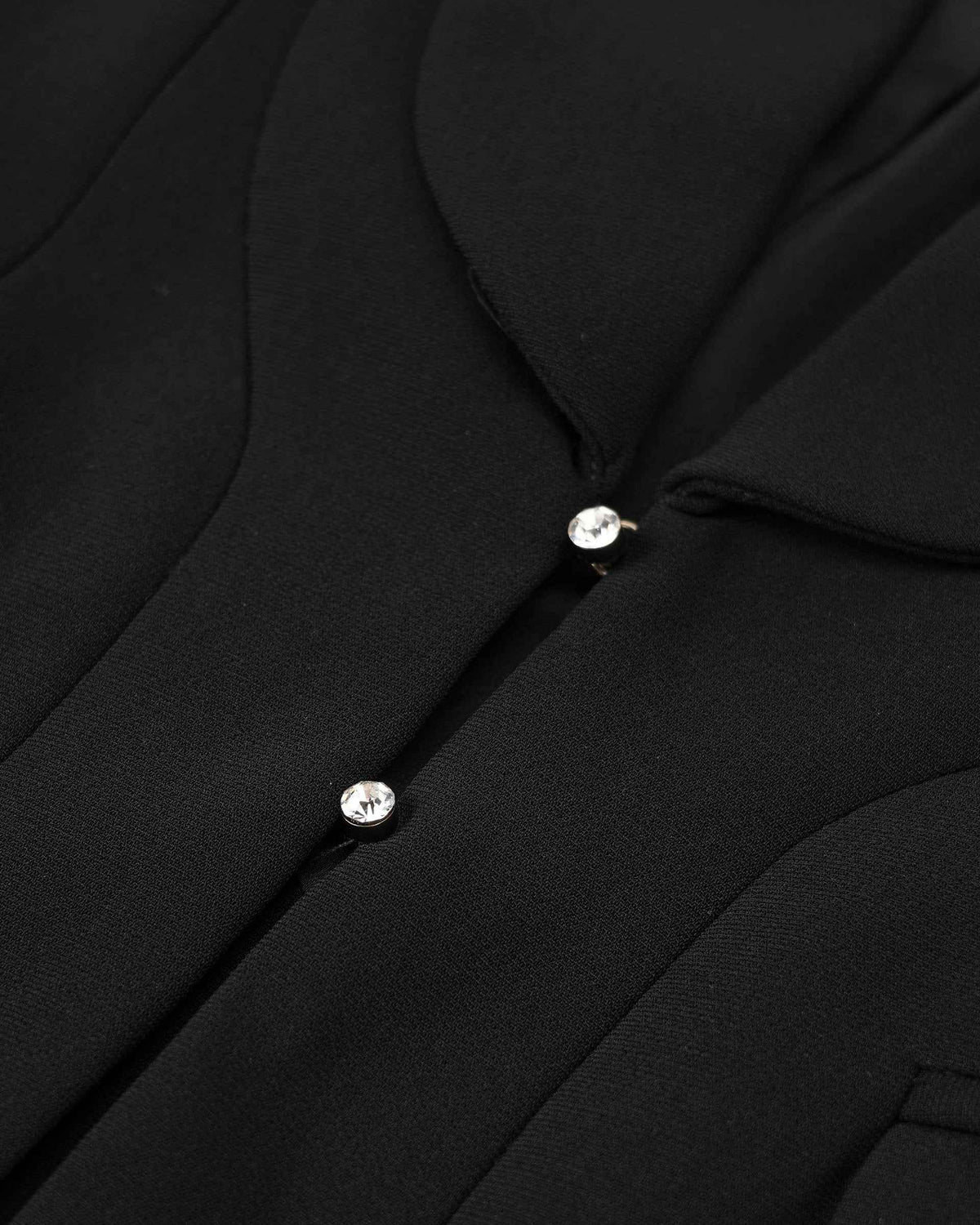 Pale decorative buttons sit beside the blazer's curved front edge.