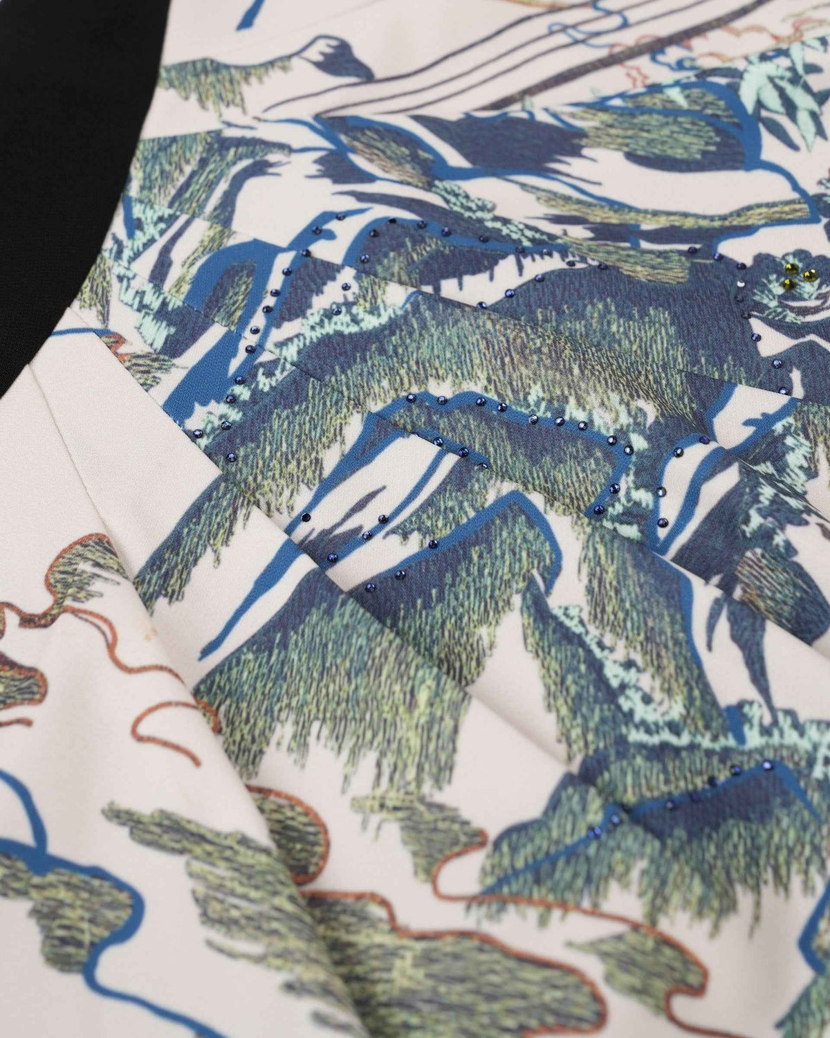 Blue and green threads define mountain-like forms across the pale fabric.