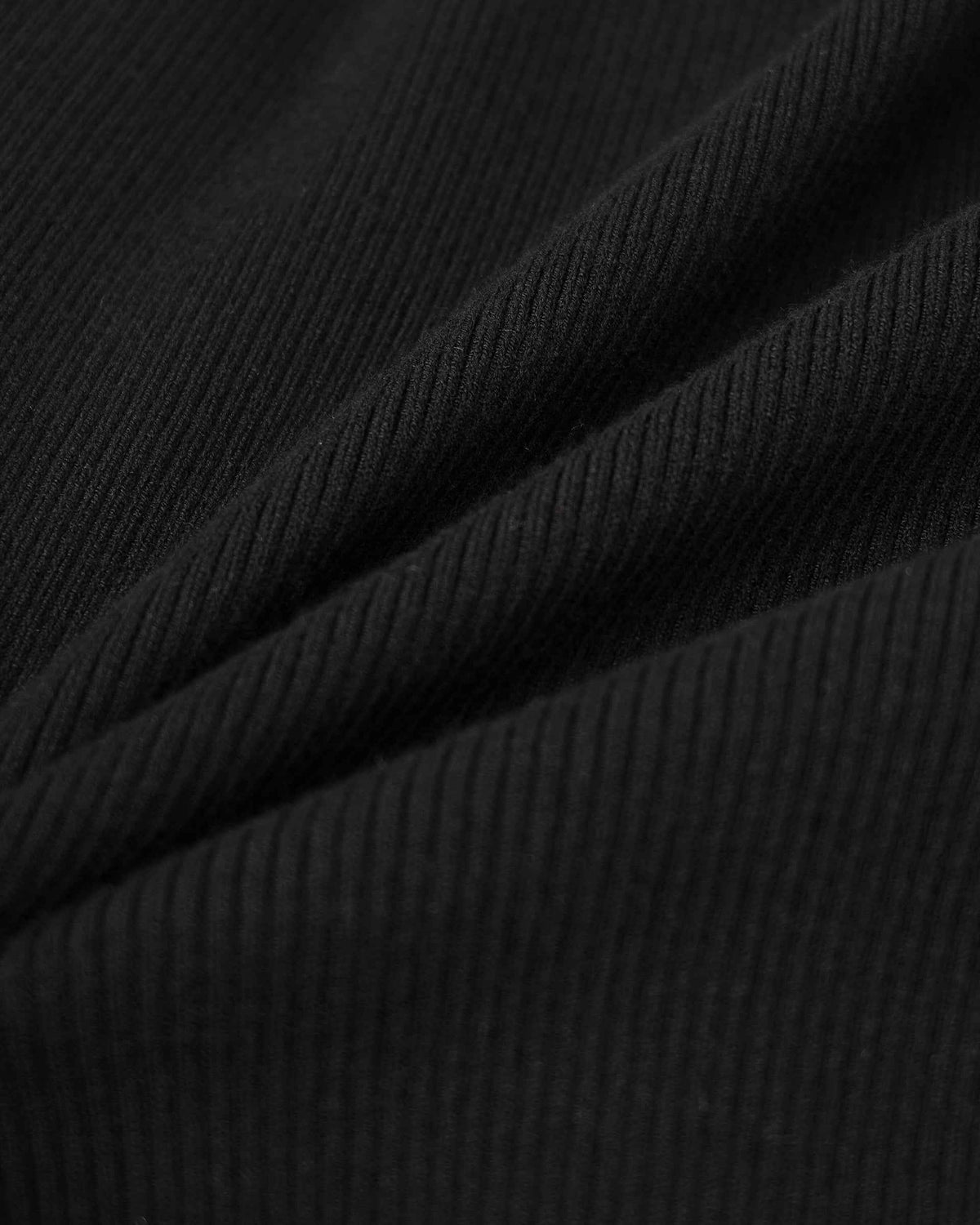 The folded knit reveals narrow ribs that catch light across the black surface.