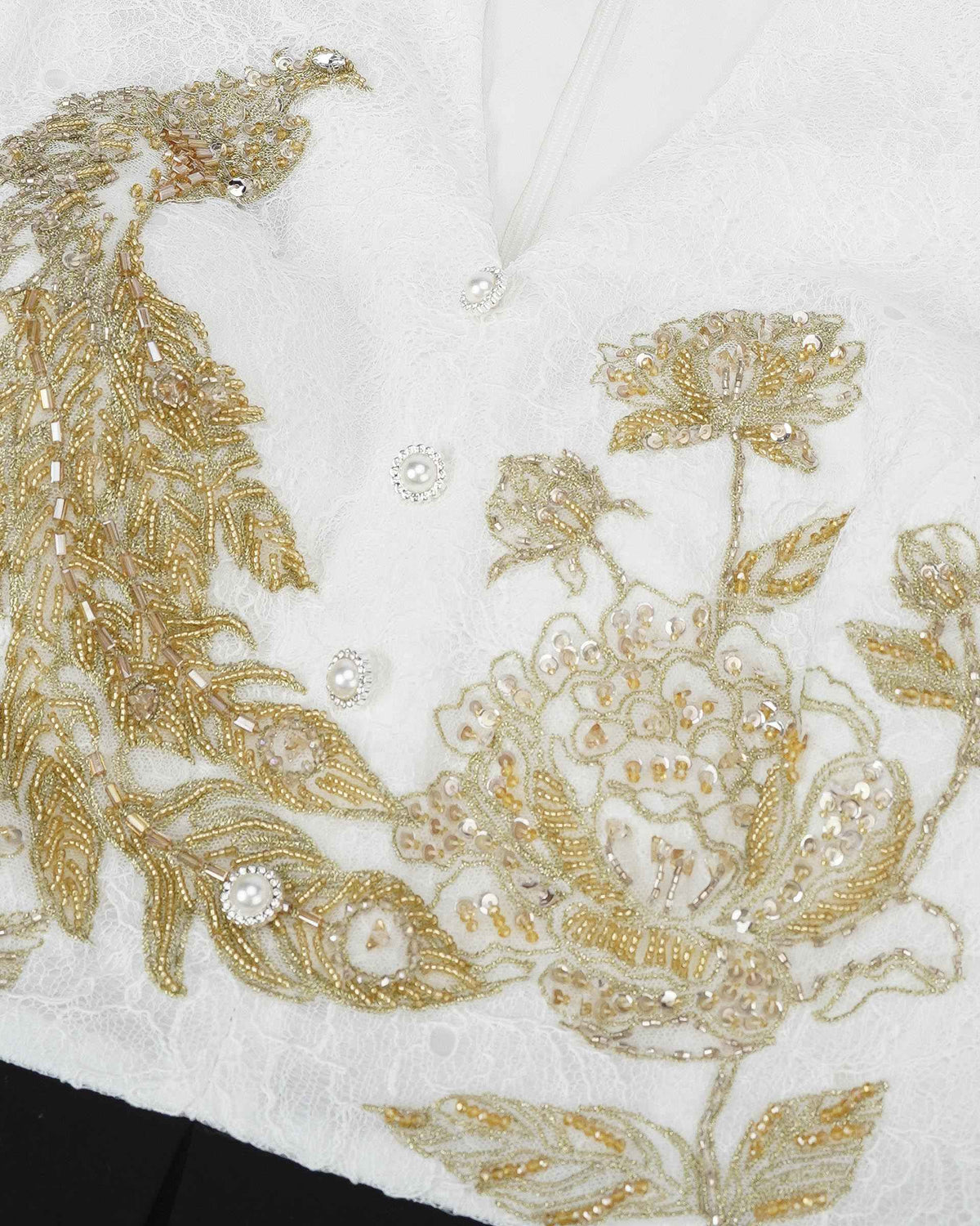 Gold-toned embroidery spreads across the ivory bodice in curling, decorative forms.