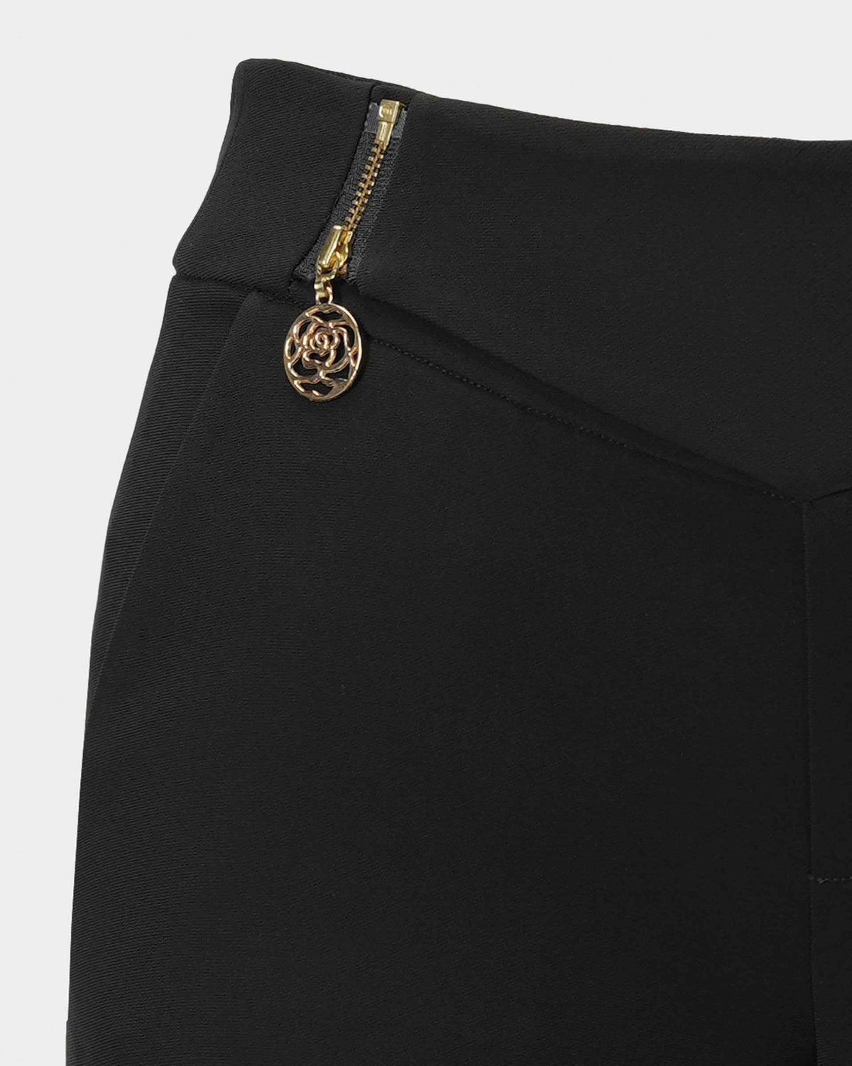A gold-toned fastening and pendant-like detail sit beside the waistband.