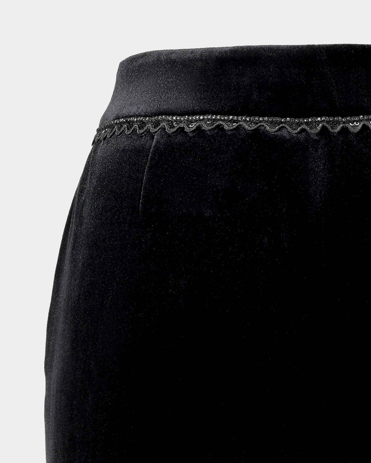 A narrow decorative edge follows the waistband, adding a small textural detail to the dark trousers.