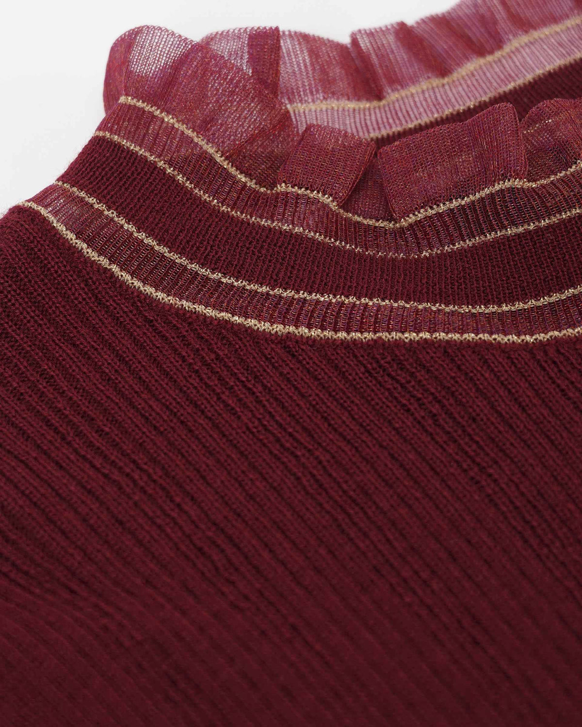 Gold-toned lines follow the burgundy neckline beneath a sheer, ruffled border.