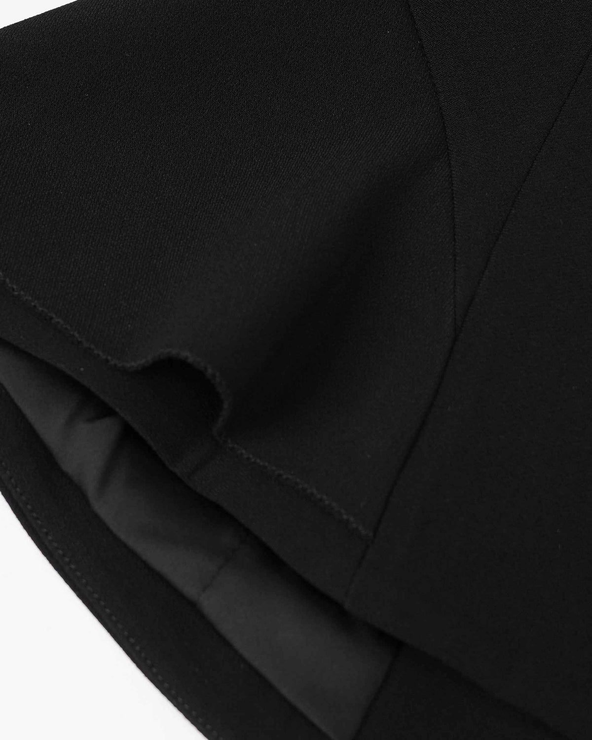Overlapping fabric edges create curved shadows within the blazer's black surface.