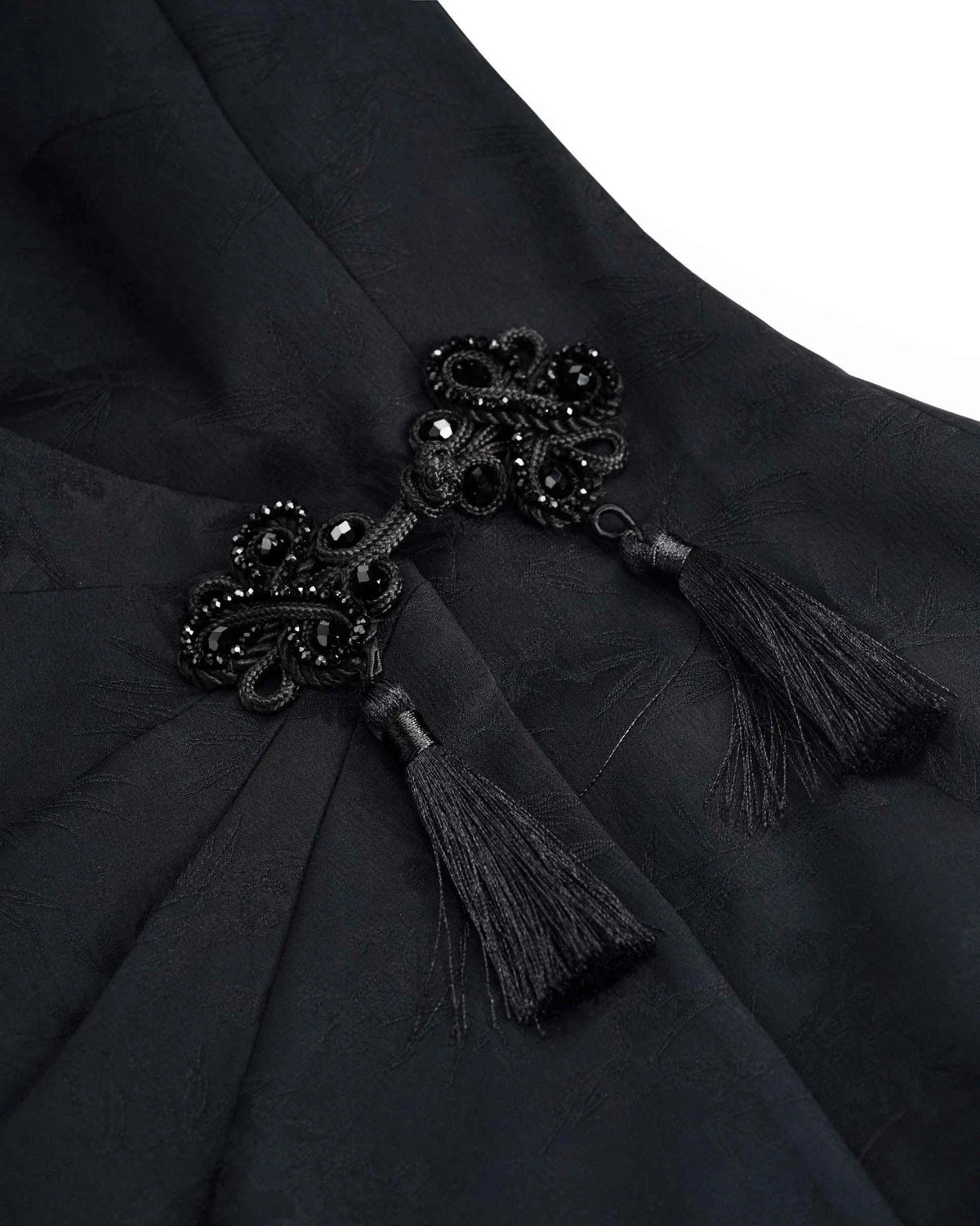 Fine dark tassels hang beneath the closely worked decorative accent.