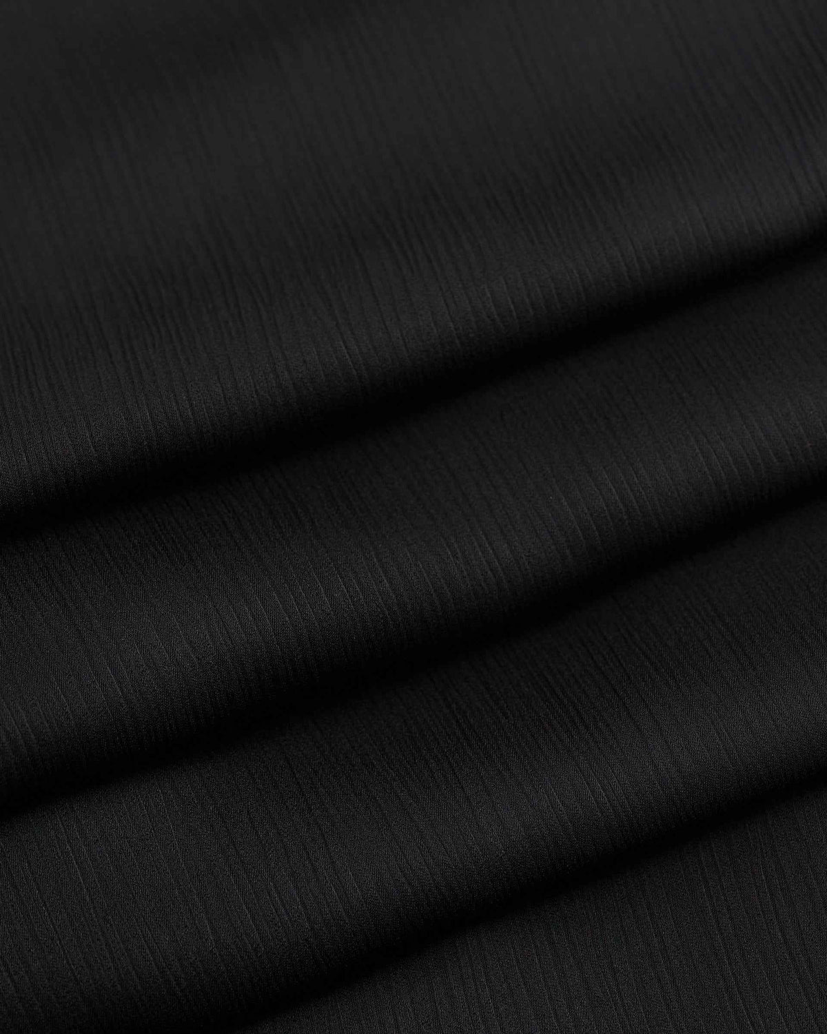 Broad folds reveal gentle changes of light across the black surface.