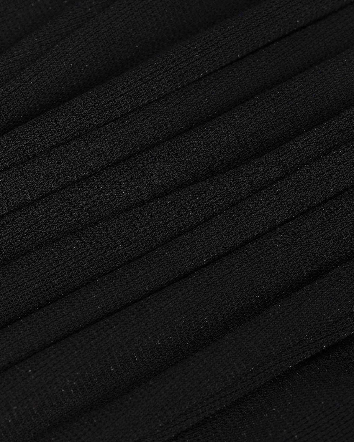 Narrow, parallel folds run across the black fabric, forming a regular rhythm of light and shadow.