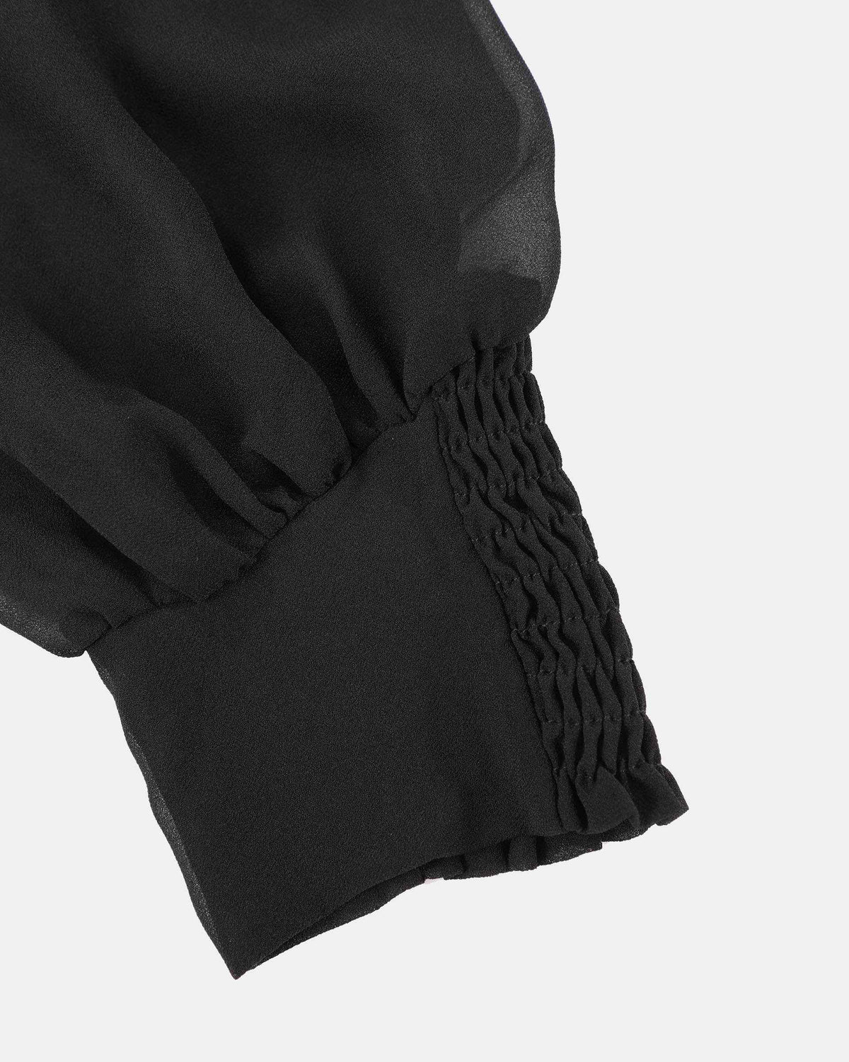 Closely spaced gathering shapes the cuff, bringing the fuller sleeve into a narrower finish.