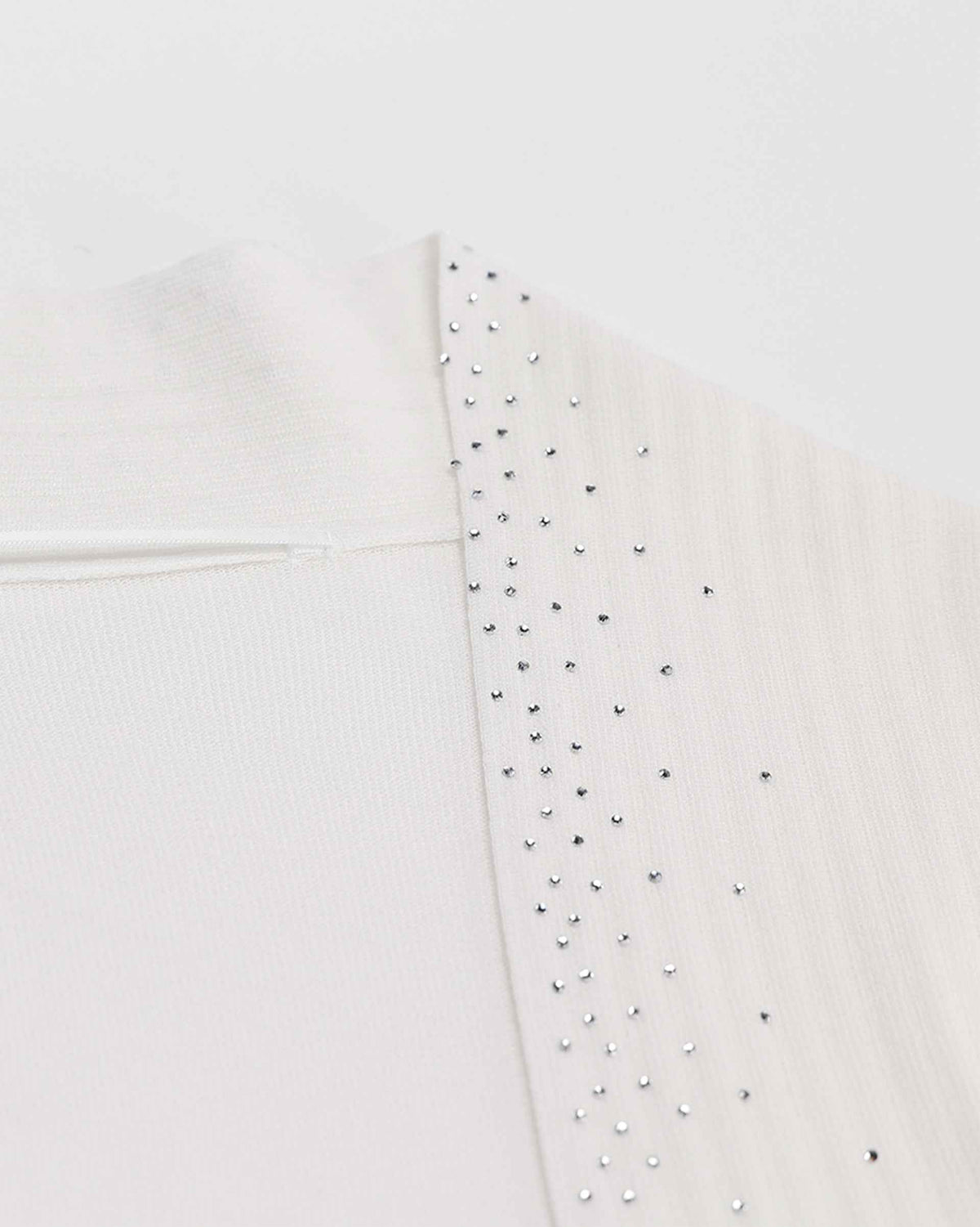Tiny reflective accents follow the pale front border, standing out gently against the light knit.