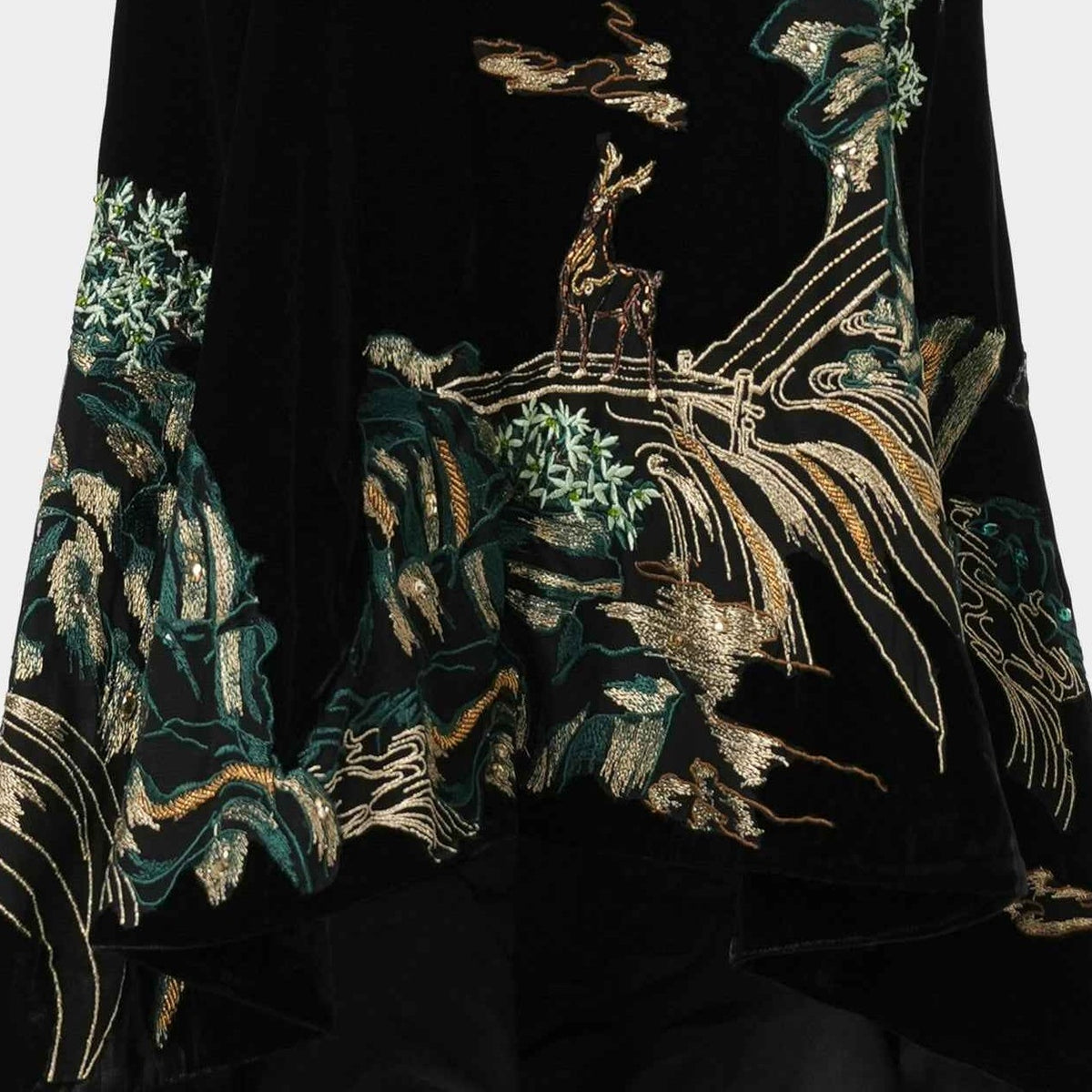 Close-up of deer, trees, rocks and flowing water embroidered in green and gold tones on the black gown.