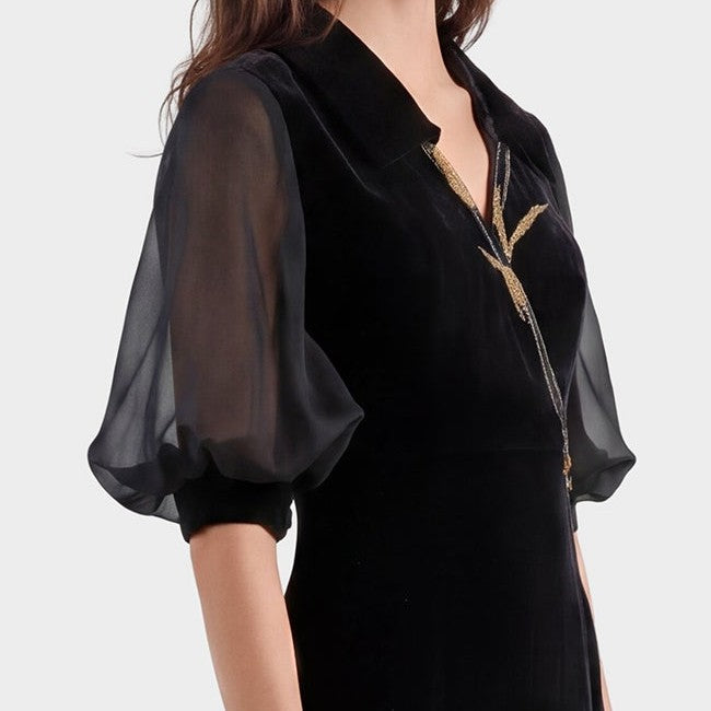 Close-up of the gown's sheer gathered sleeve, solid black cuff and gold-toned neckline embroidery.