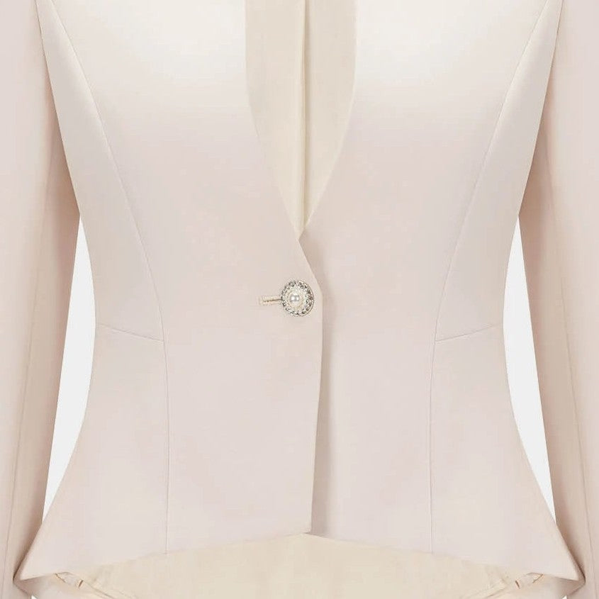 A single decorative fastening sits at the waist of the pale blazer, drawing its open edges together.