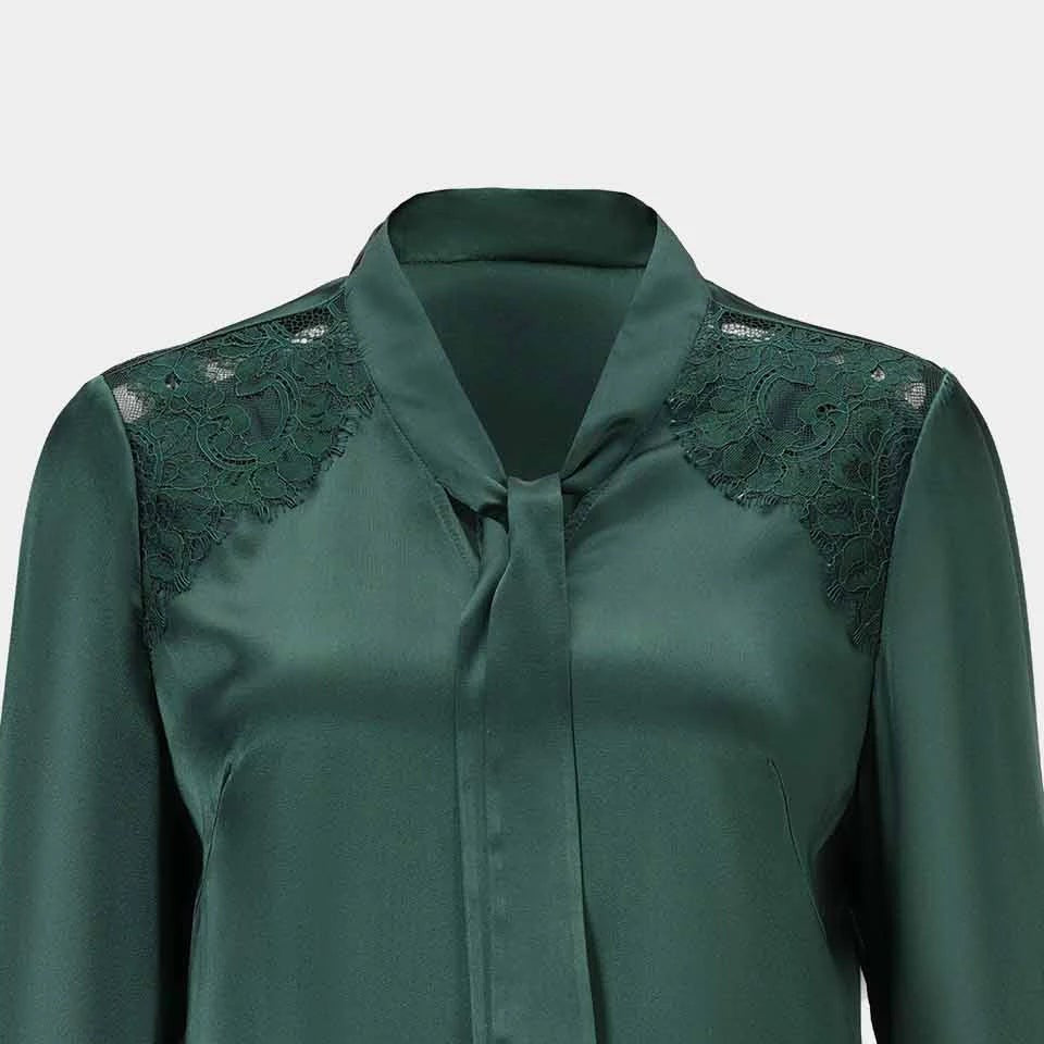 A narrow tie falls from the blouse's collar, continuing the deep green colour through the front.