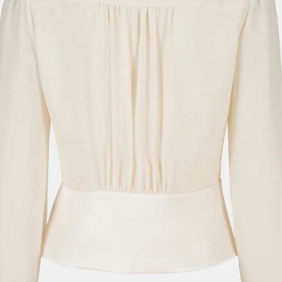 Vertical folds gather into the back waist, creating a clear contrast between fullness and structure.
